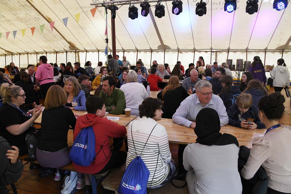 Large group of people at long tables in marque.